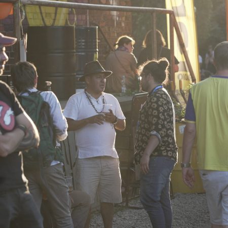Na zdjęciu widać 10 osób, dwaj mężczyźni rozmawiają. Jest ciepły, słoneczny dzień.