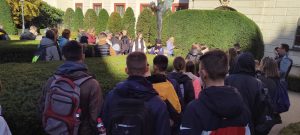 Grupowe zdjęcie nastolatków podczas spaceru z krzakami w tle oraz innymi ludźmi w oddali