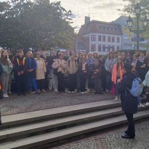 Grupowe zdjęcie z około 30 osobami podczas wizyty dzieci z domu dziecka w Żytomierzu, w tle budynek, drzewo, latarnia