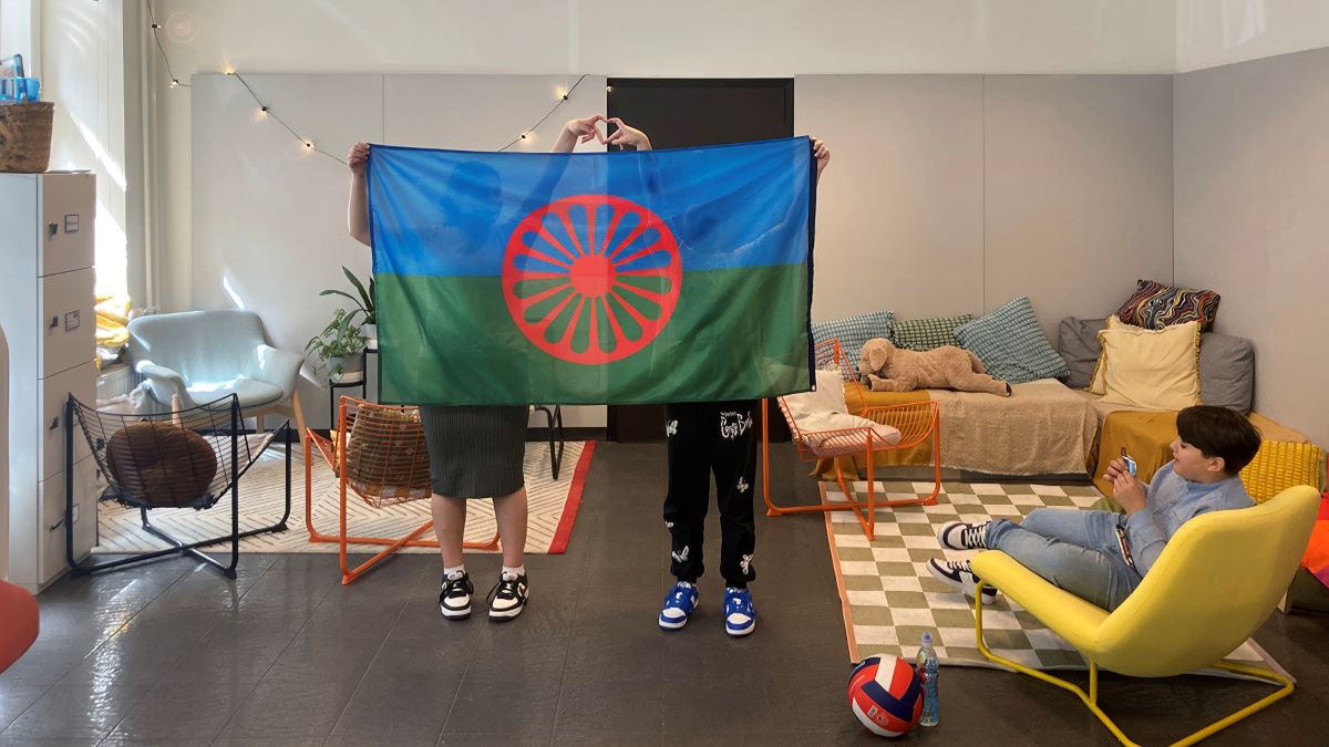 Dwie osoby trzymają romską flagę.