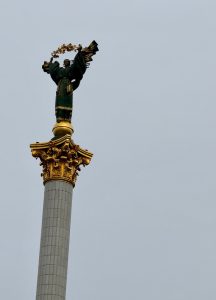 A woman’s statue stands proudly on a column, symbolizing strength and beauty on the grey sky background
