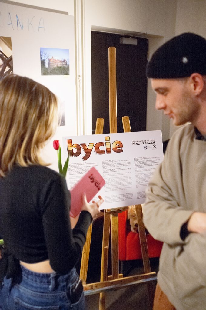 A man and woman smiling together in front of a colorful poster, showcasing their excitement and engagement with the event.