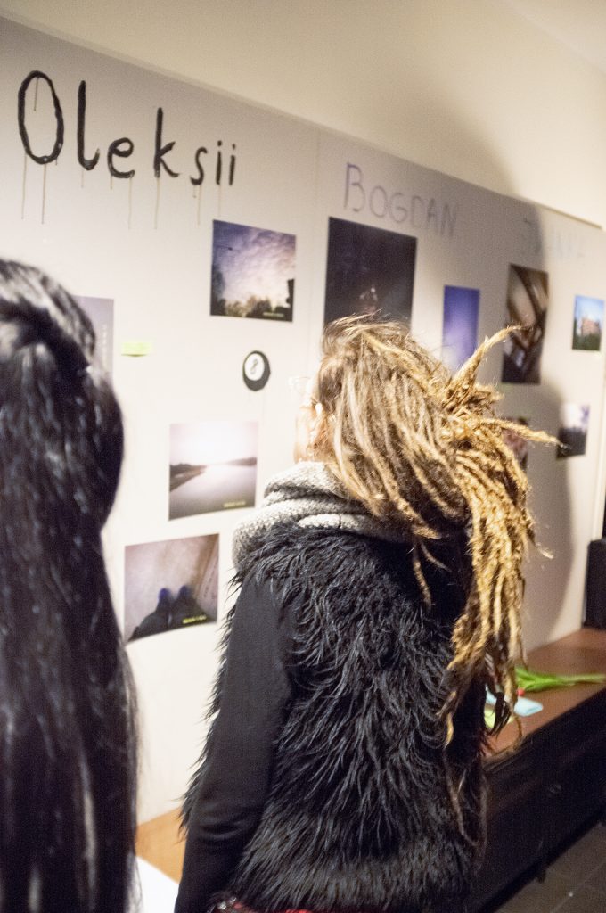 The woman in dreadlocks observe a picture-filled wall