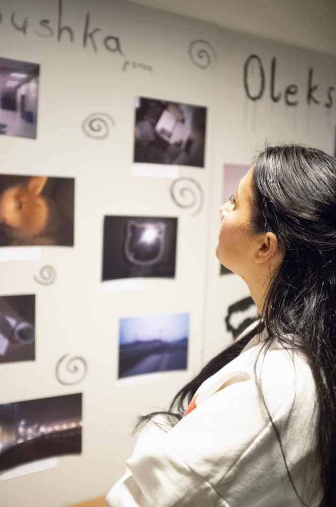 A woman gazes thoughtfully at a wall adorned with various pictures