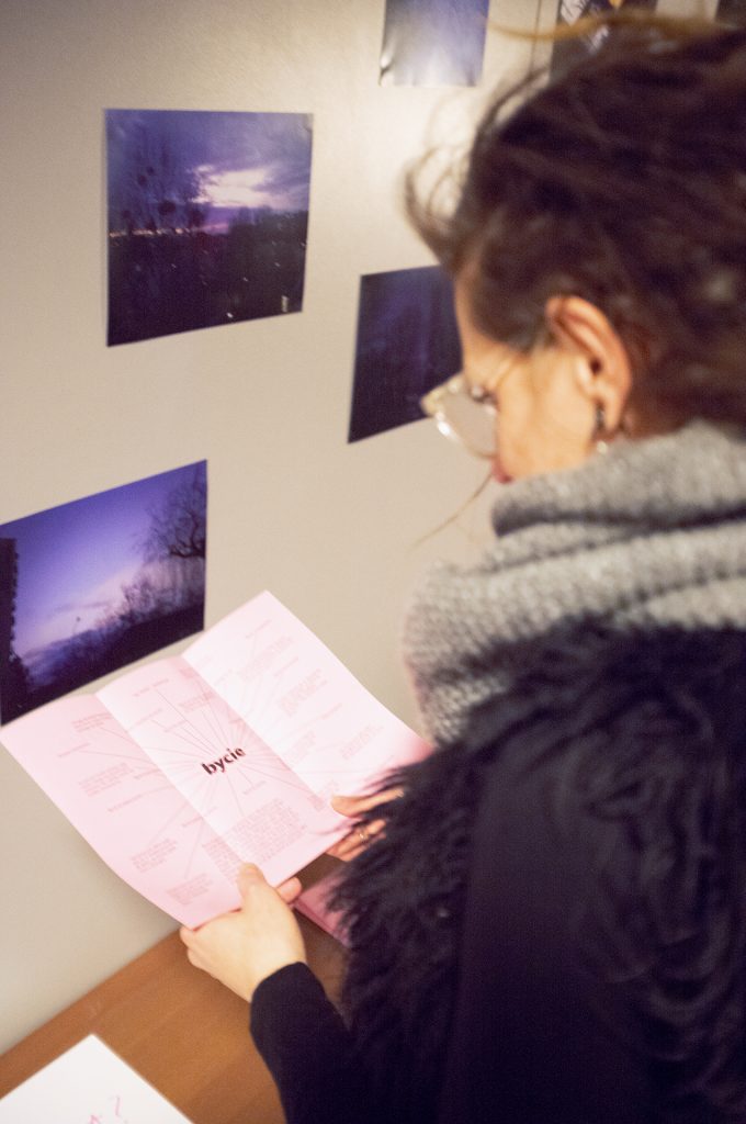 A woman studies a pink leaflet of paper, her face reflecting concentration in a warm, softly lit environment.