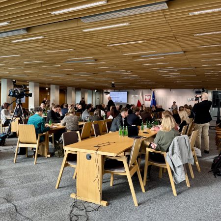 A large room with many people seated at tables, engaging in conversations and participating in discussions.