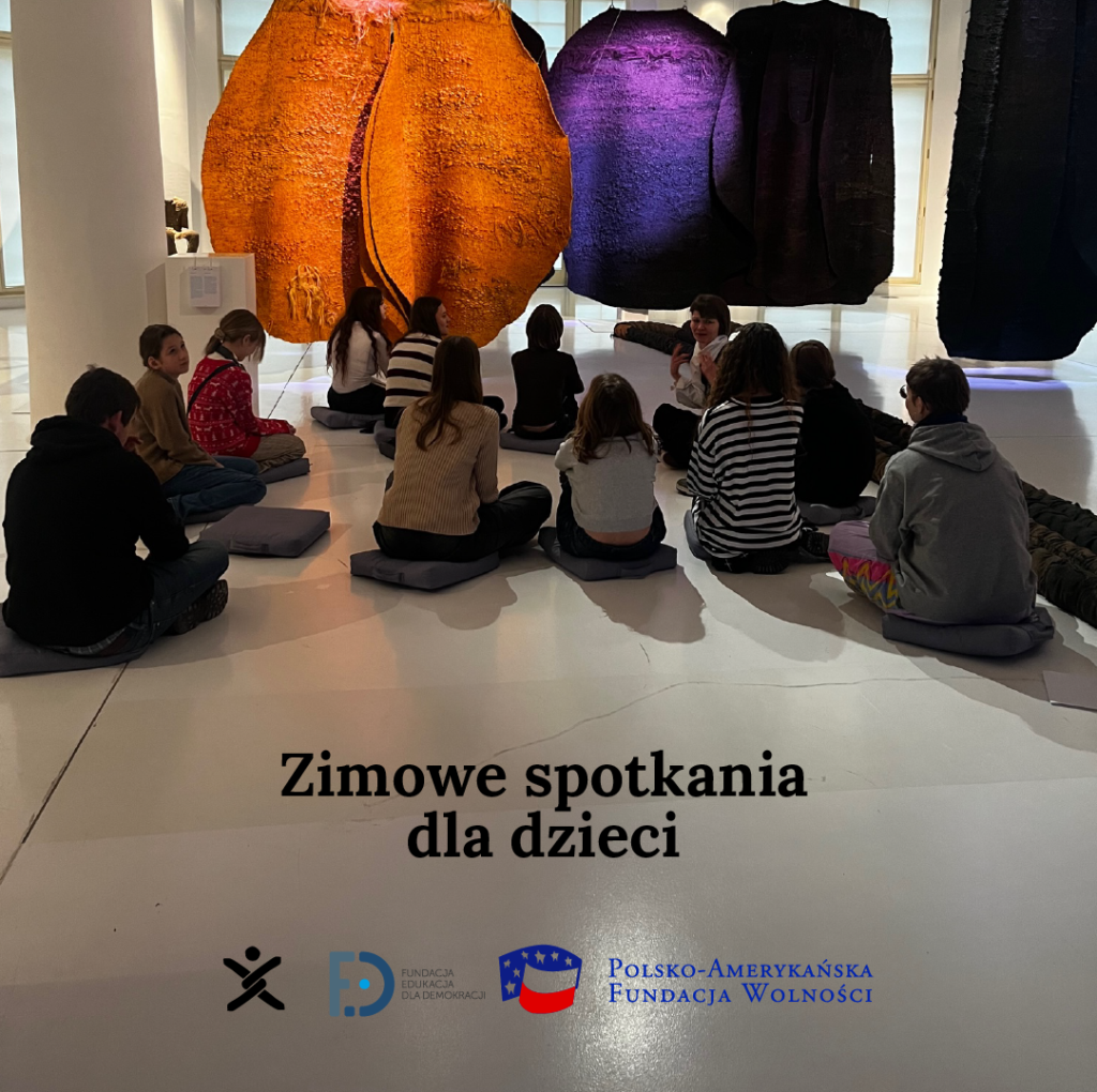 A group of teenagers sitting on the floor, focused on large orange and purple artistic objects, with the logos of Nomada, FED, and the Polish-American Freedom Foundation.