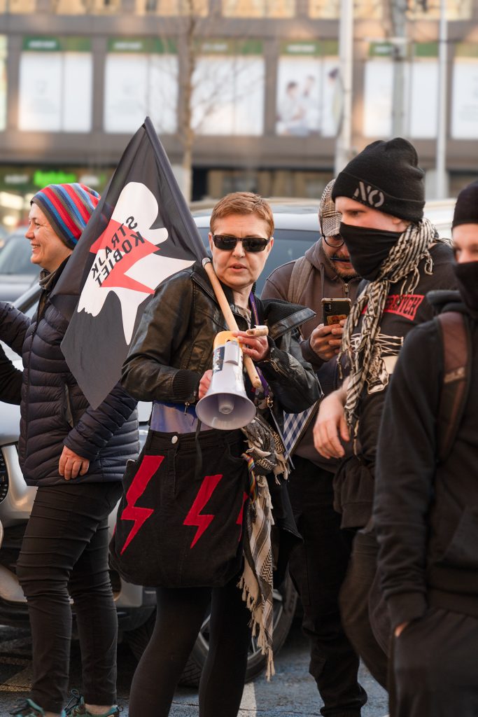 People walk together on the street, holding Woman's Strike flag in a show of unity