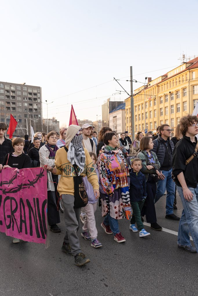 A diverse group of people walking together down the street, proudly holding a colorful banner.